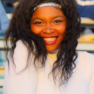 Miss Nellie, an experienced acro, dance, and gymnastics instructor, smiling in the QC Dance studio.